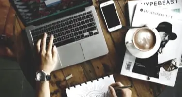 Modern Workspace on a table. There's a coffee a Mac and an Iphone e.g.